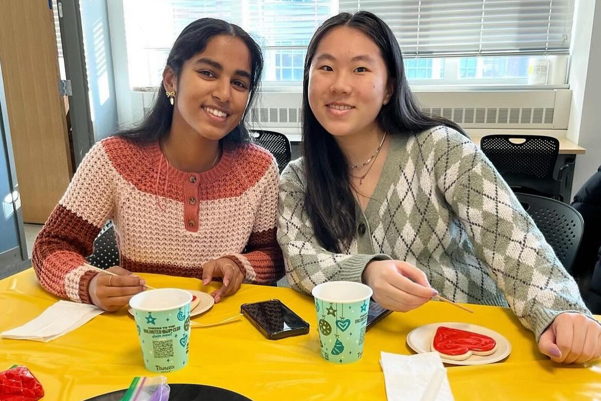 Two attendees decorate cookies together at a WISE Night In event.