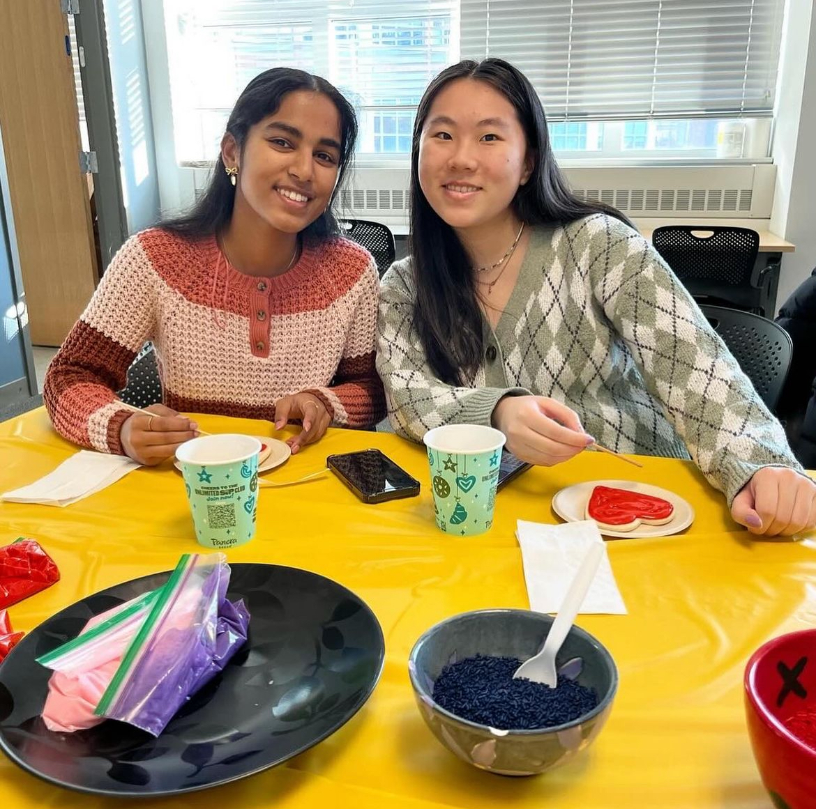 Two WISE students sitting at a table at a cookie decorating and community building event.