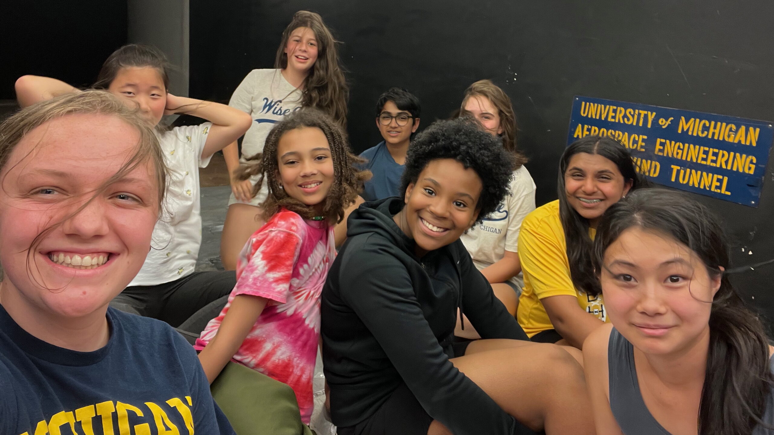 A group of middle school campers and their two counselors pose together at the University of Michigan Aerospace Engineering wind tunnel.