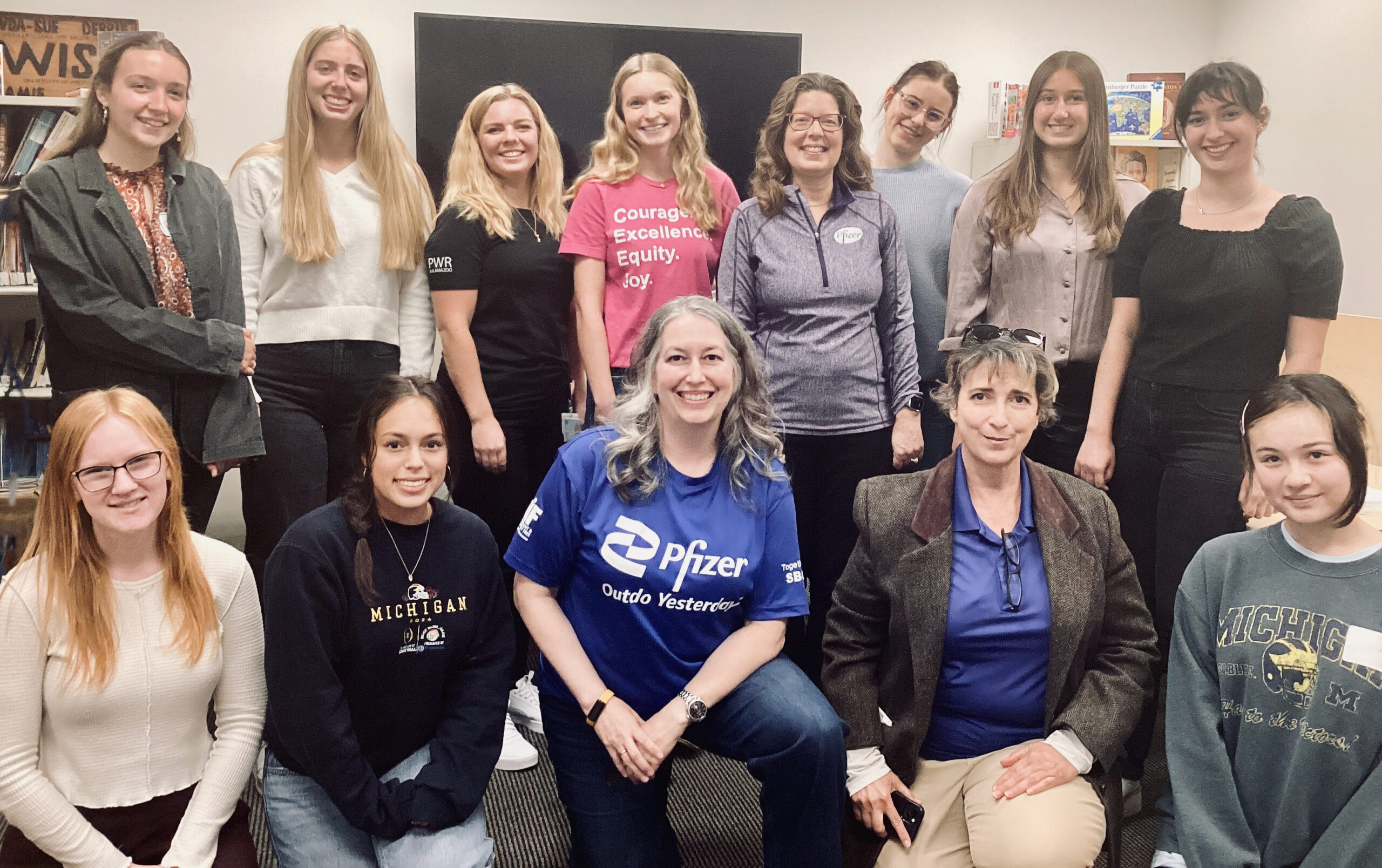 WISE students pose with the Pfizer team after a WISE & Shine panel featuring Pfizer; one shirt reads "Courage. Excellence. Equity. Joy."